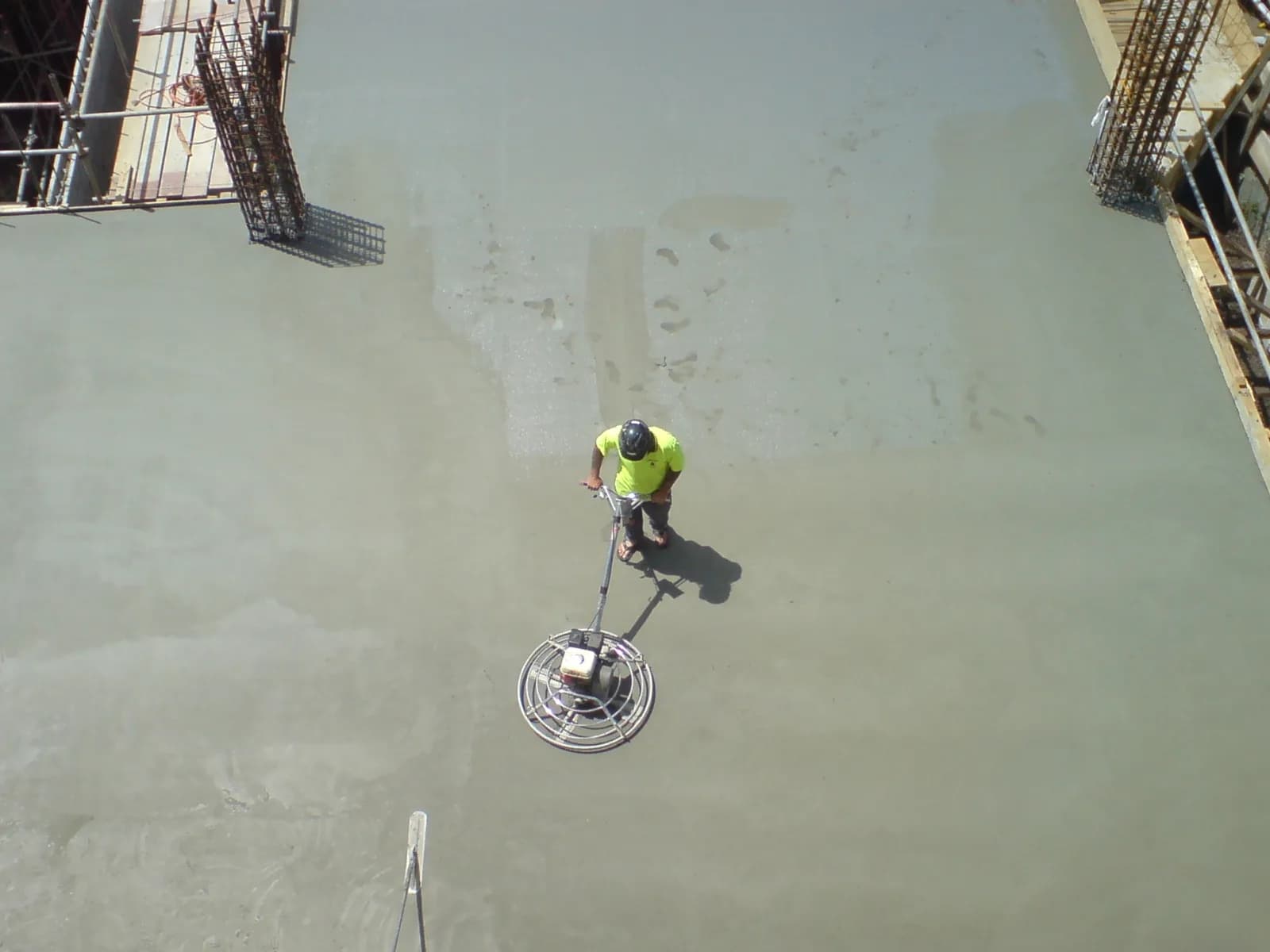 Worker polishing a fresh concrete floor with a rotary polisher